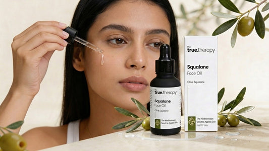 Woman applying squalane face oil with dropper next to bottle of squalane oil for skin.